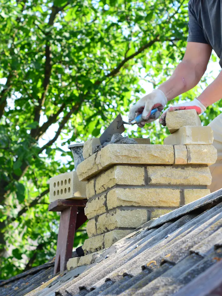 Roofer repointing a brick chimney stack