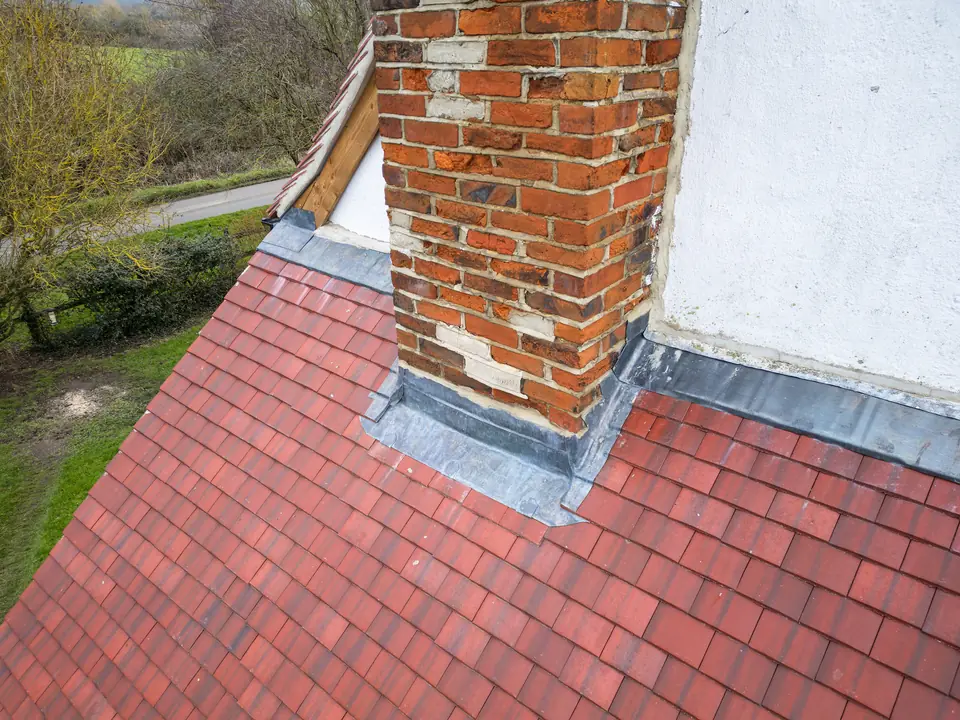 Lead flashing around the base of a brick chimney on a red tiled roof
