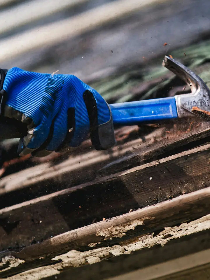 Roofer hammering at the edge of a damaged roof