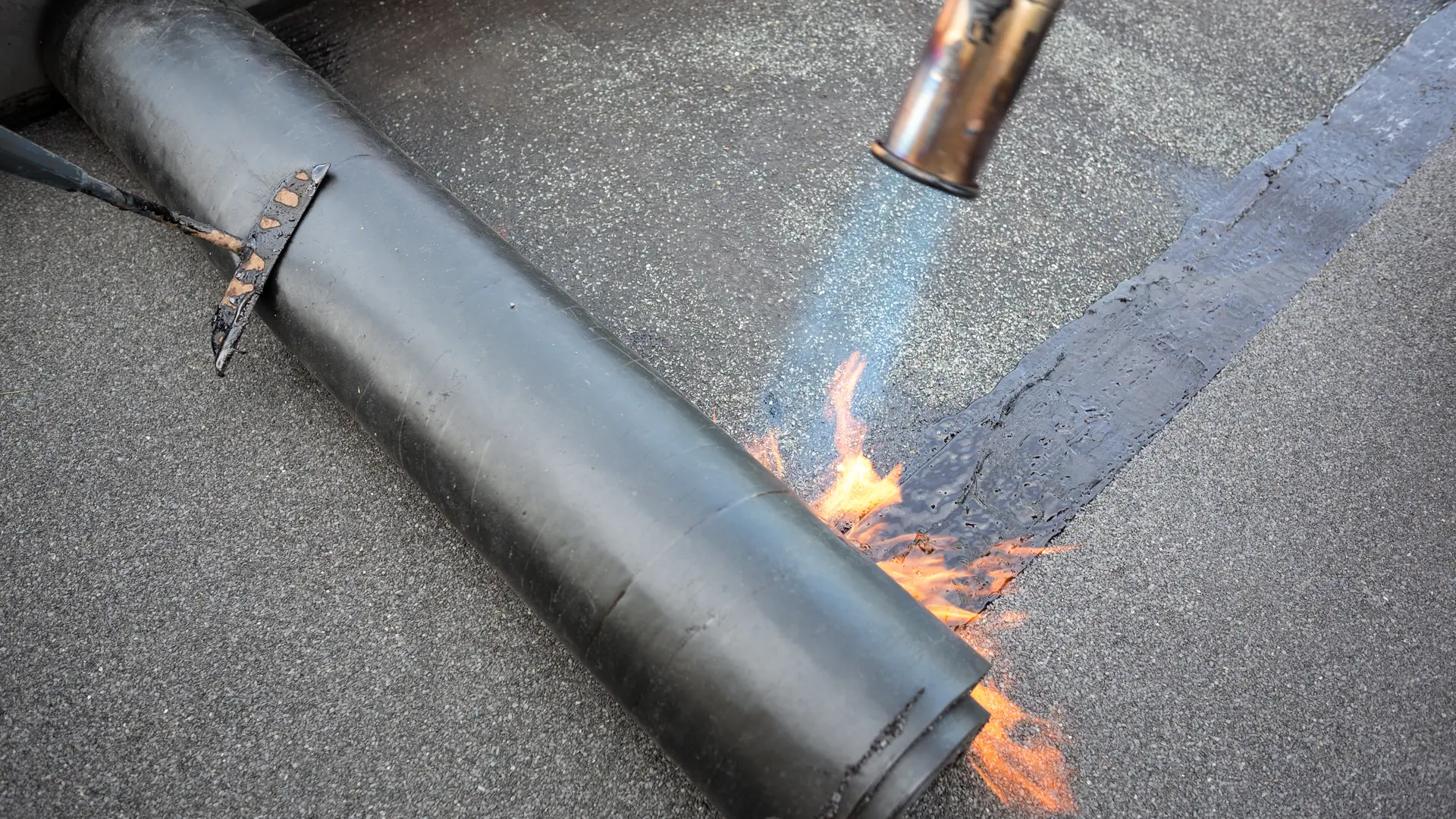 Torch-on felt being rolled out and heated on a flat roof