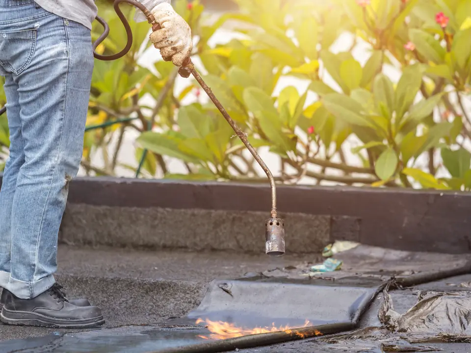 Roofer torching felt down on a flat roof