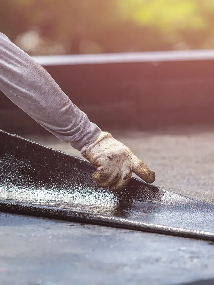 Roofer pressing a membrane edge down on a flat roof