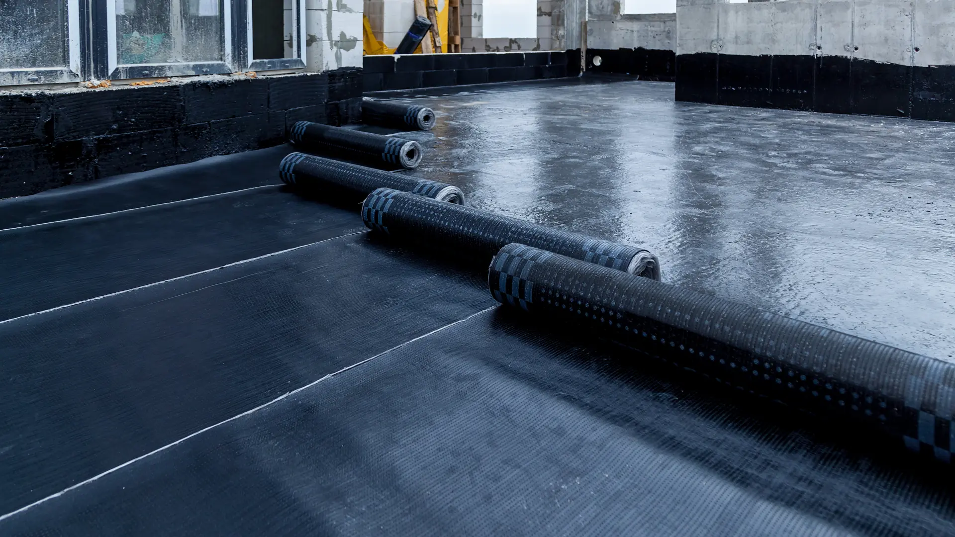 Rolls of membrane laid out across a flat roof deck