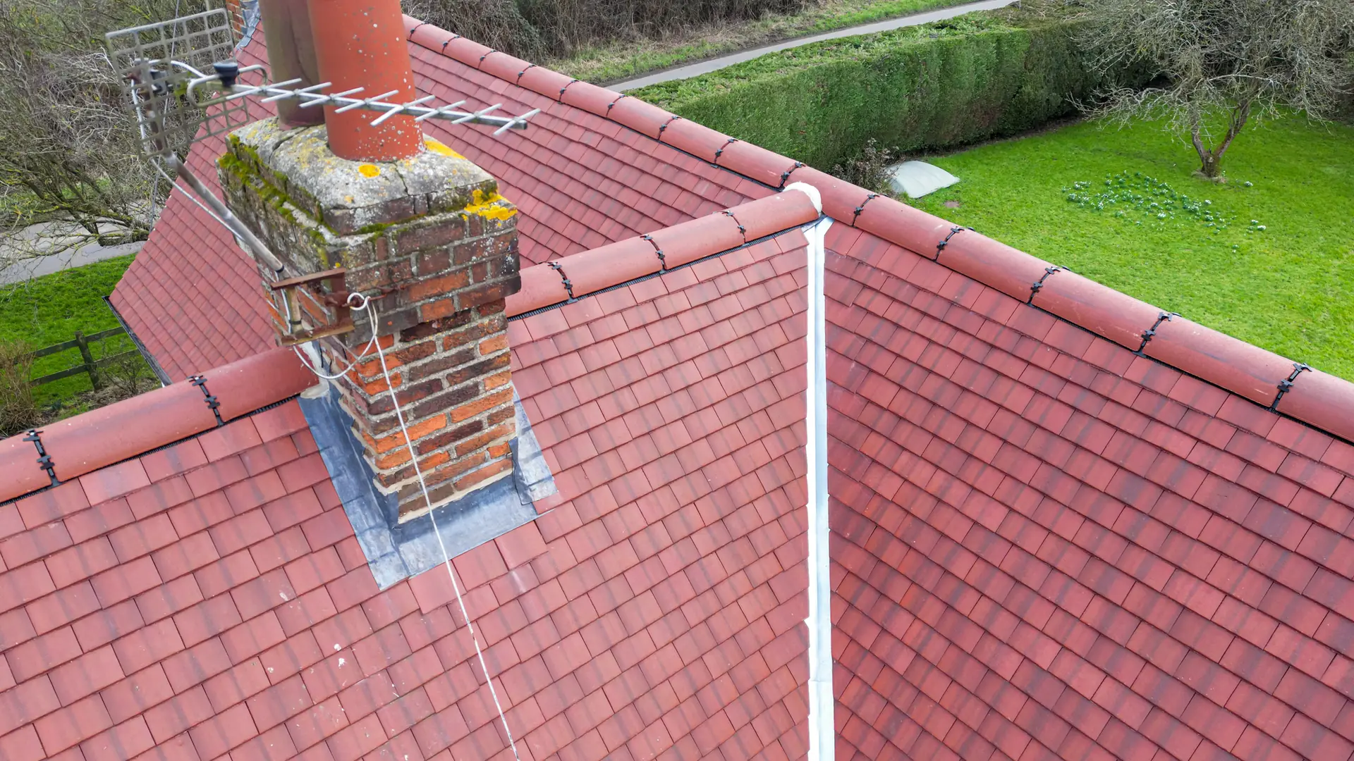 Red tiled roof with lead flashing around the base of a brick chimney