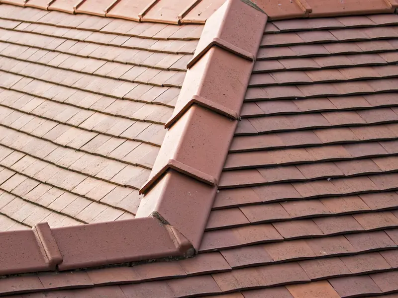 Clay ridge and hip tiles along a tiled roof