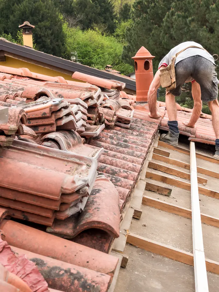 Roofer working along the battens of a clay tiled roof