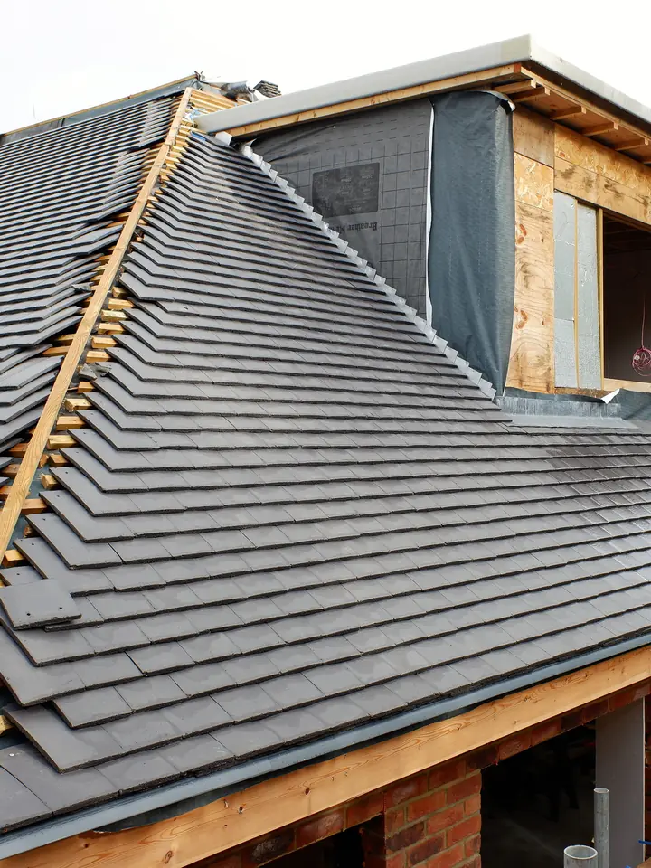Re-roof in progress with new dark tiles and a dormer